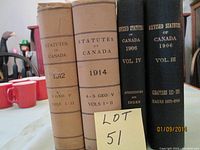 Four old hardcover statute books on a table showing titles and years 1906, 1912, 1914 with visible age wear.