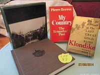 Photo of the three books standing side by side showing covers: Klondike with worn dust jacket, My Country with red and white dust jacket, and Great Railways hardcover book with photographic cover.