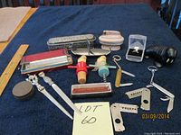 Overview of assorted small vintage collectibles including two wooden handle corkscrews, two letter openers with decorative handles, cigar cutter, utility knives, a ring in display case, and a Ronson lighter on dark cloth surface.