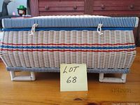 Side view of rectangular wicker sewing basket with blue and red woven stripes and blue and white striped fabric padded lid.