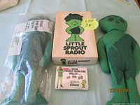 Photo of two Green Giant dolls and the Little Sprout radio in box with a small sign for the lot number