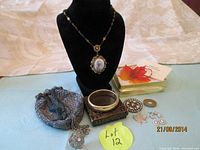 Overview photo showing all items in the lot including necklace on display bust, wrist bag purse, bracelet, brooch, earrings, and small decorative pieces.