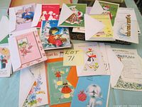 Photo showing a variety of colorful vintage and newer greeting cards spread out, some with envelopes included, showing designs of children, animals, flowers, and holiday themes.