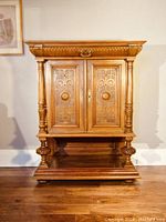 Full view of the antique carved wooden cabinet showing the overall structure with top drawer, two doors below, and three open shelves at the bottom.