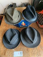 Top view of four fedora hats arranged around a Biltmore box on wooden table.