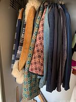 View of various men's jackets and blazers on hangers, showing textured and patterned fabrics including shearling leather, woven fabric patterns, denim, and solid wool garments in blue, grey, and black.