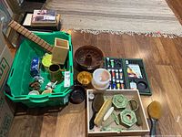 Wide-angle overview of the lot including vanity items, kitchenware, baking molds, and paint set on floor.