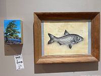 Two framed paintings on wall: one abstract Lone Pine tree scene with blue sky and river, one realistic fish illustration framed in wood.