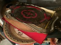 Stack of multiple decorative trays including carved Florentine trays with colors red, gold, and beige