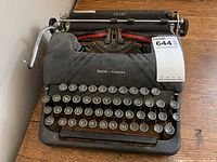 Front view of the Smith-Corona typewriter showing round black keys with white letters and silver rims, the metal body with some wear.