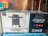 Box of propane gas barbecue grill with two burners, showing packaging details.