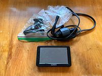 Garmin nüvi 2555LM GPS device shown with black power charger and mounting accessories, placed on a wooden surface.