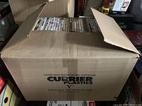 Closed cardboard box labeled 'CURRIER PLASTICS' filled with DVDs.