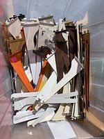 Box of assorted metal shelf brackets in different colors and sizes piled inside a plastic bin.