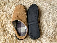 Top view and underside of one men's beige slipper on beige shaggy carpet.