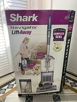 Front side of the box showing the Shark Navigator Lift-Away vacuum cleaner with highlighted features such as pet hair power brush, lift-away canister, swivel steering, anti-allergen complete seal technology, and ideal for pet owners.