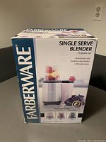 Front/side view of the Farberware single serve blender box showing product name, image of blender with cups filled with fruit, and key features.