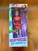 Photo of Spice Girls Barbie doll in opened box showing the doll wearing a red floral dress and missing one shoe.