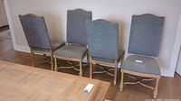 Four wooden dining chairs with blue and cream diamond patterned upholstery, arranged side by side, showing overall condition and structure of frames and upholstery.
