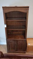 Front view of wood display case showing upper shelves and bottom cabinet