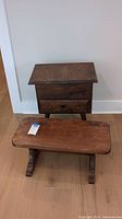 Photo showing wood end table and wood step stool on the floor against wall, both items visible with worn wood finish.