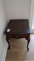 Top front view of dark wood end table with single drawer and cabriole legs