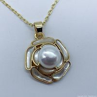Front view of gold plated floral pendant necklace with 8mm pearl center and natural seashell petals.