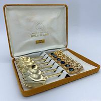 Set of six gold-plated teaspoons with koala handles and genuine Australian opal stones, arranged in original velvet-lined case.