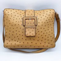 Front view of tan genuine ostrich leather shoulder bag featuring a large buckle detail on the flap and clear texture of ostrich skin.