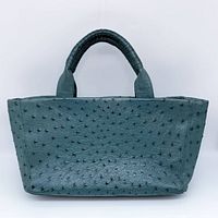 Front view of dark green ostrich leather tote handbag showing textured surface and rolled handles.