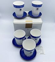 Front and top view of five cups and matching saucers in royal blue with gold trim, displayed with original box and card