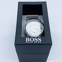 Watch displayed in original Hugo Boss black box with clear top window showing the full watch face and strap in place.