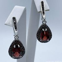 Front view of pear-shaped garnet earrings showing deep red central stones surrounded by smaller garnets on silver and gold plated setting