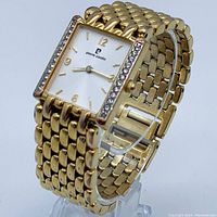 Front and side view of gold-tone Pierre Cardin watch with square white dial, gold hour markers, and Swarovski crystals on bezel.