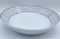 Angle front photo of Tiffany & Co. porcelain bowl showing blue Dancing 'T' pattern and gold rim.