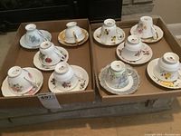 Two trays displaying five cups and matching saucers each, all porcelain with floral patterns from different brands: Royal Windsor, Royal Albert, Colclough, Salisbury, Royal Grafton. Cups upside down showing base marks, saucers underneath.