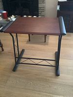 Full view of desk showing wood top and metal frame on hardwood floor environment.