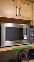 Front view of Panasonic NN-SD691S inverter microwave oven on kitchen counter, showing stainless steel front and dark window door with push button.