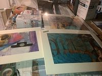 Top view showing three mixed media artworks on paper on a glass surface, includes Fragmented Sky and other pieces.