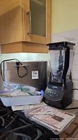 Ninja blender and Breadman bread maker shown with their accessories and manual near a kitchen counter.