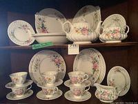 Full set showing dinner plates, bread and butter plates, cups and saucers, teapot, sugar bowl, and serving trays with floral pattern and embossed details.