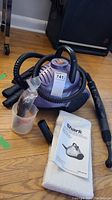 Shark steam cleaner unit with attached hose and nozzle, microfiber pad and manual laid on floor.