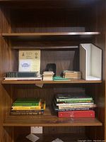 Bookshelves with a variety of books including reference and general interest titles. Books arranged in stacks and some upright, showing variety in book thickness and cover colors.