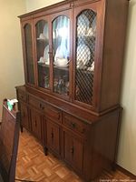 Front angle view showing the wooden buffet base with drawers and cabinet doors, topped by the glass door hutch with lattice metal on outer doors