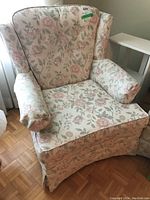 Front angle view of the wingback living room chair showing floral pattern upholstery and padded armrests.