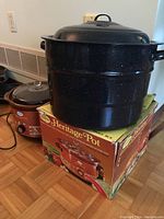 Blue speckled multi-tier canning pot stacked on top of its box with Sunbeam Heritage Pot crock pot nearby on the floor.