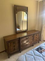 Front view of the wood dresser with mirror attached, showing drawer fronts, wood finish, and mirror design.