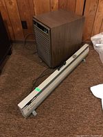 Side view of Electrohome dehumidifier with woodgrain finish and front metal grille placed on brown carpet.