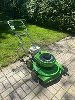 Side view of mower showing deck, wheels and handle outdoors