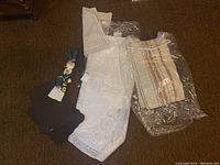 Overview of assorted linens including lace curtain, striped curtain or runner, bath mat, placemats, and decorative ribbon pieces